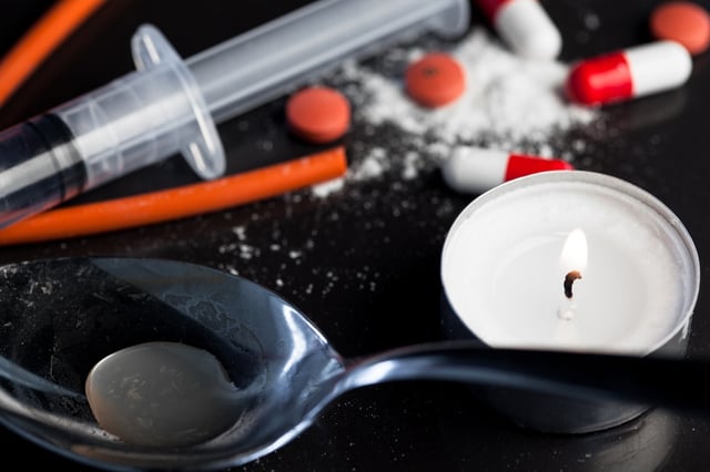 Drug paraphernalia including cooking spoon candle syringe tourniquet powder pills and tablet.jpeg